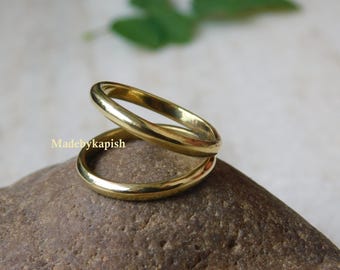Op de afbeelding: Een gouden ring met een eenvoudig, minimalistisch ontwerp. De ring is gemaakt van twee banden die met elkaar zijn verweven.