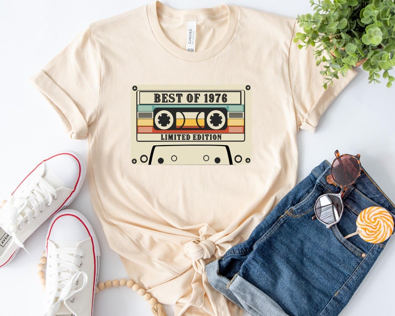 May include: A beige t-shirt with a vintage cassette tape graphic. The tape has the text "Best of 1976 Limited Edition" printed on it.
