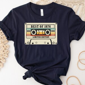 May include: A navy blue t-shirt with a vintage cassette tape graphic. The tape has the text "BEST OF 1976" and "LIMITED EDITION".