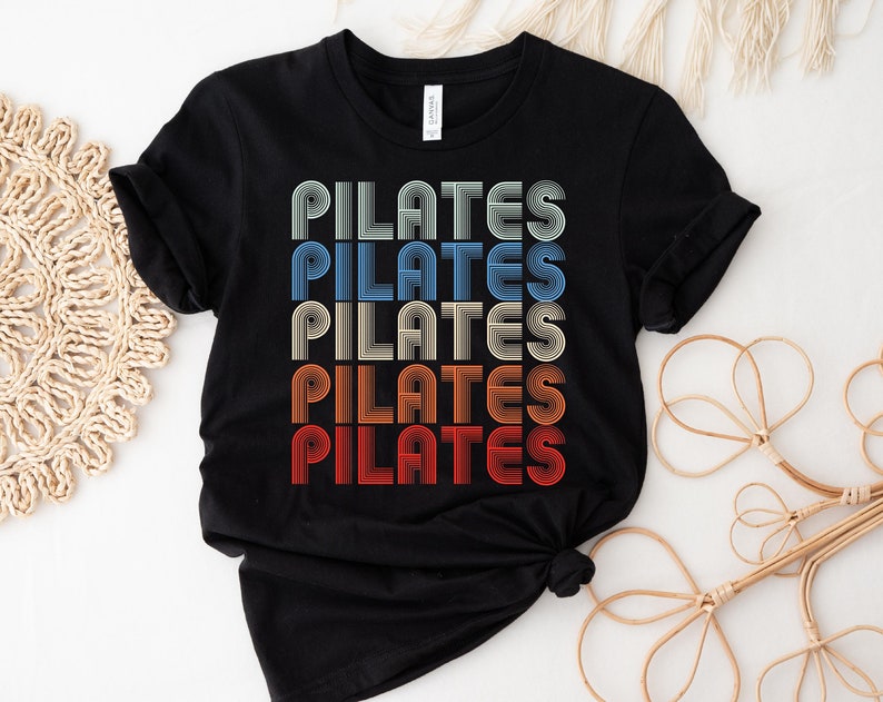 May include: Black t-shirt with the word "PILATES" repeated five times in a retro, rainbow-colored font.