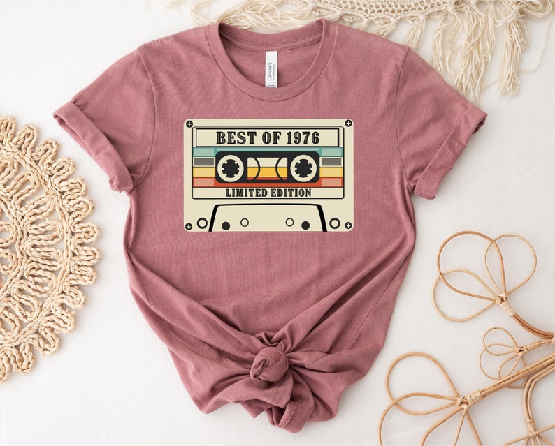 May include: A mauve t-shirt with a vintage cassette tape graphic. The tape has the text "Best of 1976 Limited Edition".