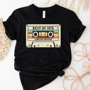 May include: Black t-shirt with a vintage cassette tape graphic that says "Best of 1976 Limited Edition".