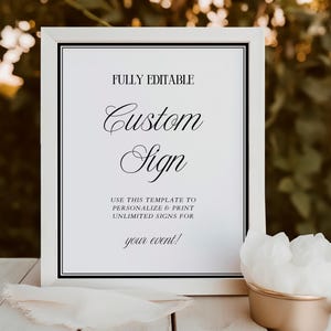 May include: A white framed sign with the text "FULLY EDITABLE Custom Sign" in elegant script. The sign is on a white surface with a gold-colored container holding white tissue paper. The sign is designed for personalization and printing.
