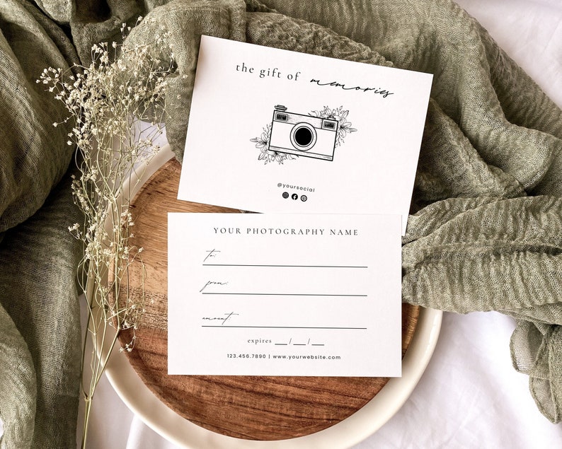 May include: A white gift certificate with black text that reads "the gift of memories" and features a black and white illustration of a camera with floral accents. The text "YOUR PHOTOGRAPHY NAME" is also included on the certificate.
