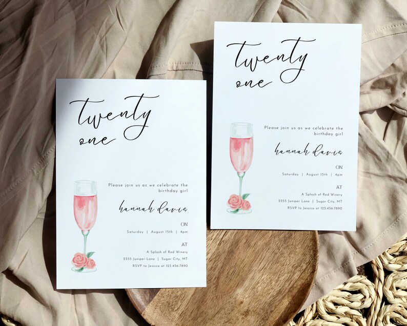 May include: Two white cards with black calligraphy that says "Twenty One" and a pink watercolor illustration of a champagne flute with pink roses. The text on the cards says "Please join us as we celebrate the birthday girl Hannah Davis on Saturday, August 15th at 4pm at A Splash of Red Winery, 1355 Juniper Lane, Sugar City, MT. RSVP to Jessica at 123.456.7890."