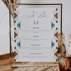 May include: A gold framed sign with a southwestern design border. The sign reads "The Bar" with a horseshoe symbol and lists various beer, wine, spirits, and cocktails.