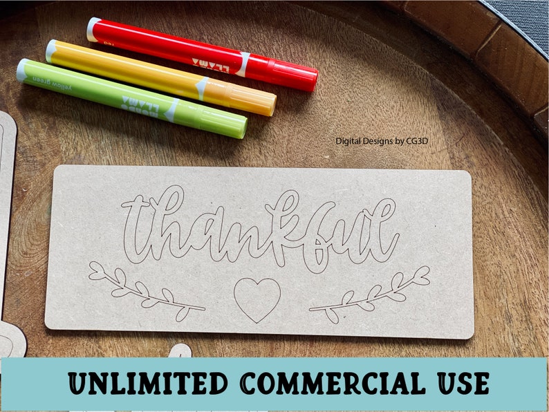 May include: A wooden sign with the word "thankful" written in a cursive font. The sign also has a heart and two branches with leaves. The sign is on a wooden surface with three markers.