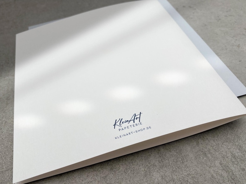 May include: A white card with a black logo that says "KleinArt Papeterie" and "kleinart-shop.de" in a handwritten font.