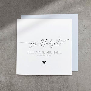 May include: A white card with black text that says "zur Hochzeit" Juliana & Michael 8 August 2025. A small black heart is below the date.