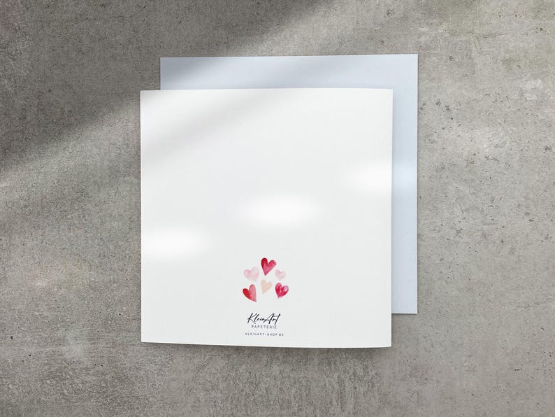 May include: Blank white card with a pink and red heart design on the back. The card reads "Kleinfeld Papeterie" and "Old Hart - 10002-00".
