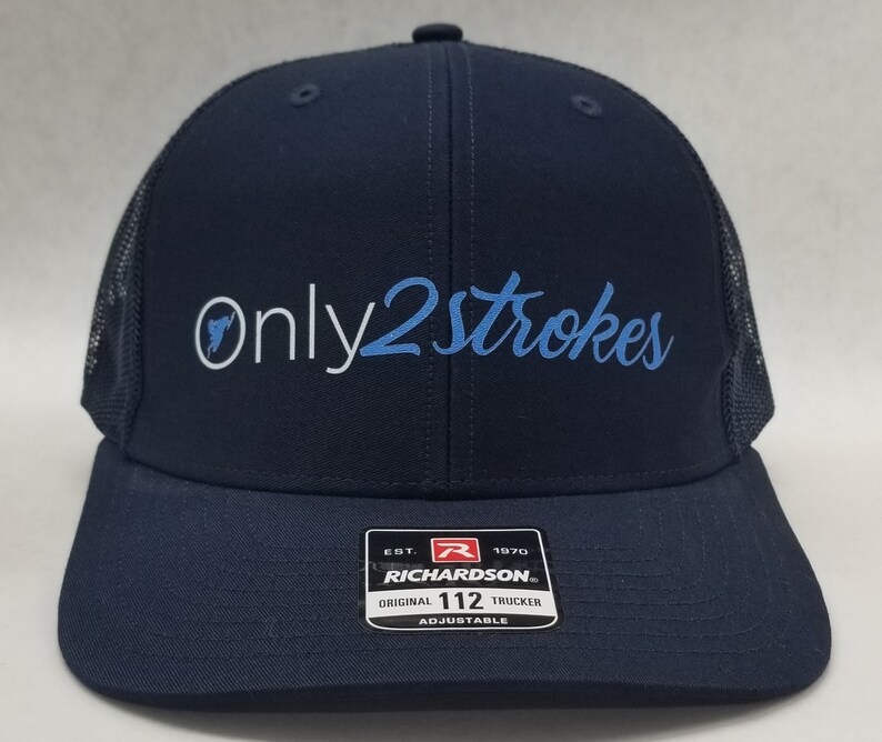 May include: A navy blue trucker hat with a black mesh back. The hat has white embroidery that says "Only2Strokes" in a cursive font. The text "Only" is in white and the text "2Strokes" is in light blue. The hat has a black and white label on the back that says "Richardson" and "Original 112 Trucker Adjustable".