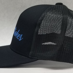 May include: Black trucker hat with a blue embroidered logo that says "Stokes".
