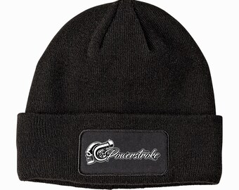 Peut inclure: Bonnet en tricot noir avec un écusson rectangulaire. L'écusson présente un graphique blanc d'un turbocompresseur et d'un crâne, avec le mot "Powerstroke" en écriture stylisée. Un accessoire décontracté.