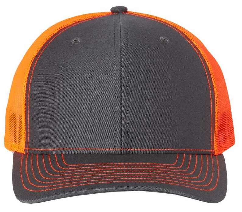 May include: A charcoal gray and orange trucker hat with a mesh back. The hat has a curved brim and a contrasting orange stitching detail.