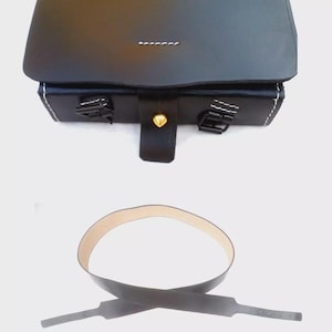 Può includere: Borsa in pelle nera con chiusura a patta, cuciture bianche e due fibbie metalliche. Include una cintura in pelle nera abbinata con interno marrone chiaro. La borsa ha un bottone dorato.
