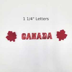 Peut inclure: Lettres rouges à paillettes épelant "CANADA" avec deux écussons de feuilles d'érable rouges. Le texte "1 1/4" Letters" est au-dessus des lettres. Les lettres et les feuilles d'érable sont sur fond blanc.
