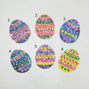 May include: Six sequined Easter egg patches in various colors. The eggs feature designs with pink, purple, green, yellow, and gold sequins. Each egg has a unique pattern, perfect for crafting or embellishing.