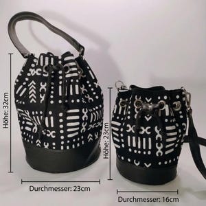 May include: Two black and white patterned bucket bags. The larger bag is 32 cm high with a 23 cm diameter, and the smaller bag is 23 cm high with a 16 cm diameter. Both bags have black leather bases and drawstring closures.