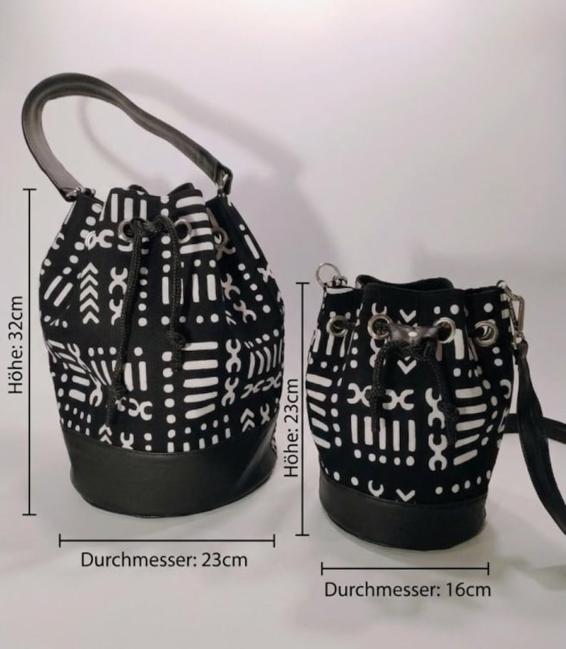 May include: Two black and white patterned bucket bags. The larger bag is 32 cm high with a 23 cm diameter, and the smaller bag is 23 cm high with a 16 cm diameter. Both bags have black leather bases and drawstring closures.