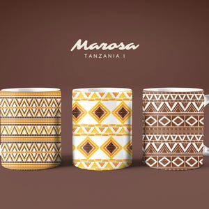 Peut inclure: Trois mugs en céramique blanche avec des motifs tribaux dans les tons marron, jaune et blanc. Les mugs présentent des motifs géométriques, notamment des triangles et des losanges, sur un fond marron. Le texte "Marosa Tanzania I" est en haut.