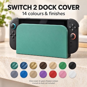 Könnte beinhalten: Eine türkisfarbene Dockingstation-Abdeckung für eine Spielkonsole mit dem Text SWITCH 2 DOCK COVER und 14 colours & finishes. Darunter zeigen 14 kreisförmige Farbmuster die verfügbaren Optionen, mit dem Text One cover in your chosen colour.