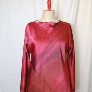 Op de afbeelding: Een langarmige, rode zijden blouse met een gegolfde halslijn en een subtiel ombre-effect. De blouse is op een witte mannequin.