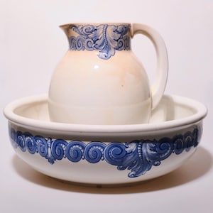 Könnte beinhalten: Eine Vintage-Keramikkrug mit Henkel, in einer passenden Schüssel. Beide Teile weisen ein blaues Blumendesign an den Rändern auf. Krug und Schüssel sind wahrscheinlich Teil eines Waschbeckensets.