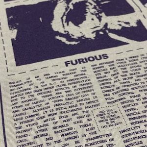 May include: A close-up of a black and white printed graphic t-shirt with the word "FURIOUS" in bold letters. The text describes rabies, a viral disease that can be transmitted to humans through bites from infected animals. The text also includes a phone number for the closest rabies vaccine.