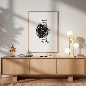May include: A framed black and white print of a wristwatch hangs above a wooden cabinet. The cabinet has three doors and sits on a light-colored rug. A gold lamp with spherical bulbs and a wooden chair are to the right.