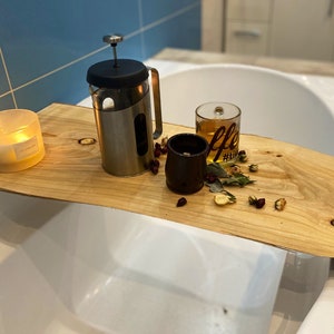 May include: A wooden bath tray with a lit candle, a French press, a mug of tea, and dried flowers and herbs.
