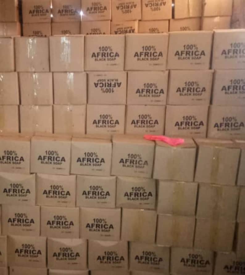 Puede incluir: Una pila de cajas de cart&oacute;n llenas de jab&oacute;n negro 100% Africa. Las cajas est&aacute;n apiladas en un almac&eacute;n o lugar de almacenamiento.