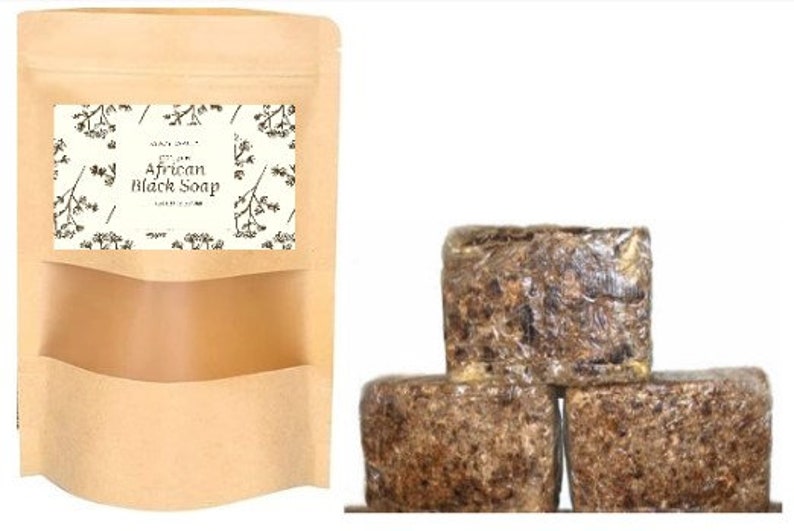 Puede incluir: Tres barras de jab&oacute;n negro africano en una bolsa de papel marr&oacute;n. El jab&oacute;n es marr&oacute;n oscuro y tiene una textura rugosa. La bolsa tiene una etiqueta que dice "100% Jab&oacute;n Negro Africano Puro".