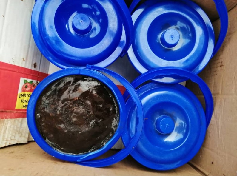 Puede incluir: Cuatro contenedores de pl&aacute;stico azul con tapas. Un contenedor est&aacute; abierto y lleno de una sustancia marr&oacute;n oscura.
