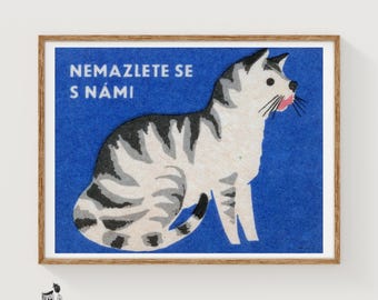 May include: A framed rectangular print featuring a white and grey tabby cat against a solid blue background. The cat is shown in profile facing right with a pink tongue visible. The text "NEMAZLETE SE S NÁMI" is printed in white in the upper left.