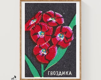 May include: A rectangular print featuring a cluster of vibrant red carnation flowers with white and blue centres, set against a textured black background. A green stem and leaf extend diagonally across the image, with the Cyrillic text ГВОЗДИКА.