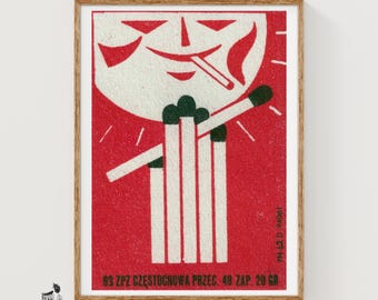 May include: A rectangular print featuring a red background with a stylized white moon face smoking a match. Below, a cluster of white matches with dark green tips is displayed. Text at the bottom reads 63 ZPZ CZESTOCHOWA PRZEC. 48 ZAP. 20 GR.