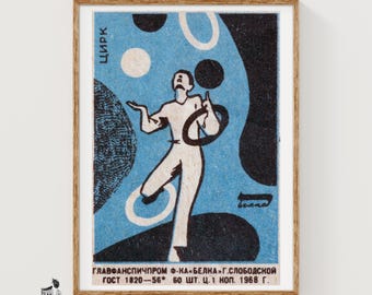 Puede incluir: Una impresión de etiqueta de caja de cerillas vintage con un gráfico azul y negro de un artista haciendo malabares con aros. El texto incluye la palabra "ЦИРК" y letras cirílicas rusas en la parte inferior, "ГЛАВФАНСПИЧПРОМ Ф-КА БЕЛКА Г.СЛОБОДСКОЙ ГОСТ 1820-56 60 ШТ. Ц. 1 КОП. 1968 Г."