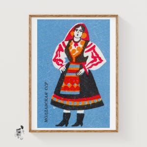 Könnte beinhalten: Gerahmte Vintage-Illustration einer Frau in traditioneller moldauischer Tracht. Die Frau trägt ein schwarzes Kleid mit bunter Schürze, roter Kopfbedeckung und weißen Ärmeln mit roten Akzenten. Der Hintergrund ist hellblau, mit dem Text "Moldavskaya SSR".