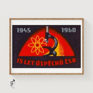 May include: A framed rectangular print featuring a dark background with the years 1945 and 1960 in grey. A central red and yellow semi-circle contains a yellow atomic symbol and a black microscope. The text 15 LET ÚSPĚCHŮ ČSR is in red.
