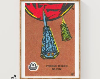 Puede incluir: Una impresión de etiqueta de caja de cerillas vintage con dos cohetes estilizados azules y verdes sobre un fondo naranja texturizado con un arco rojo en la parte superior. El texto dice DRAVA y SVEMIRSKI BRODOVI NA PUTU, con el número 10 en la esquina.