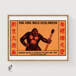 May include: Vintage matchbox art featuring a gorilla holding a match against an orange background. The text "KING KONG MACIS KESELAMATAN" is at the top, with Chinese characters on the sides. The bottom text reads "SINCERE MATCH & TOBACCO FACTORY SDN. BHD."