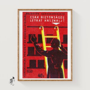 Pode incluir: Impressão de cartaz vintage emoldurada em madeira. O cartaz apresenta uma escada amarela e a silhueta de uma pessoa a estender-se para cima. O fundo é vermelho com formas retangulares pretas e texto húngaro.