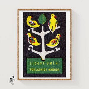 May include: A framed print featuring a black background with a white stylized tree. Four yellow birds with colorful wing patterns are perched on the branches. Below the tree is a green rectangular box with the text LIDOVÉ UMĚNÍ POKLADNICE NÁRODA.