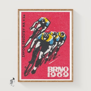Puede incluir: Impresión de póster vintage que representa una carrera ciclista. La obra de arte muestra ciclistas en movimiento, sobre un fondo rojo, con el texto "BRNO 1969". Los ciclistas visten uniformes amarillos, azules y negros. También se ve el texto "ZAVOD DRUZSTEV NA 4 km".