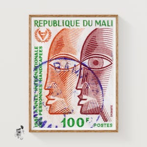 May include: Framed vintage postage stamp from Mali with two stylized faces in orange and burgundy. The stamp has French text and the value "100 F POSTES". A unique piece of art.