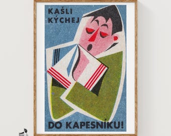May include: A framed vintage-style poster featuring a stylized illustration of a person coughing into a handkerchief. The text reads KAŠLI KÝCHEJ DO KAPESNÍKU! The figure wears a green jacket against a blue background with red and white accents.