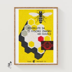May include: Framed vintage poster with a yellow background and a stylized bee illustration. The poster features text in Czech and a honeycomb design. The bottom right corner has a red seal and the text "JEDNOTA".