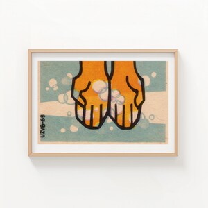 May include: A framed print featuring a stylized illustration of two orange hands with black outlines, cupping white bubbles. The background is light blue with white dots and a horizontal white stripe. The text "UZVB-69" is in the lower left corner.