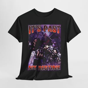 May include: Black t-shirt with a graphic print of three figures holding guns. The text "IT'S PAST MY BEDTIME" is printed in red on the shirt.