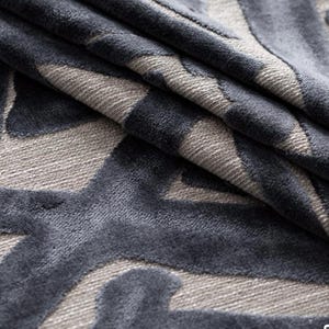 Puede incluir: Primer plano de una tela plegada con un patr&oacute;n geom&eacute;trico repetitivo. El dise&ntilde;o presenta tonos de gris y azul oscuro. La tela tiene una textura suave y aterciopelada, con pliegues y sombras que a&ntilde;aden profundidad al dise&ntilde;o.